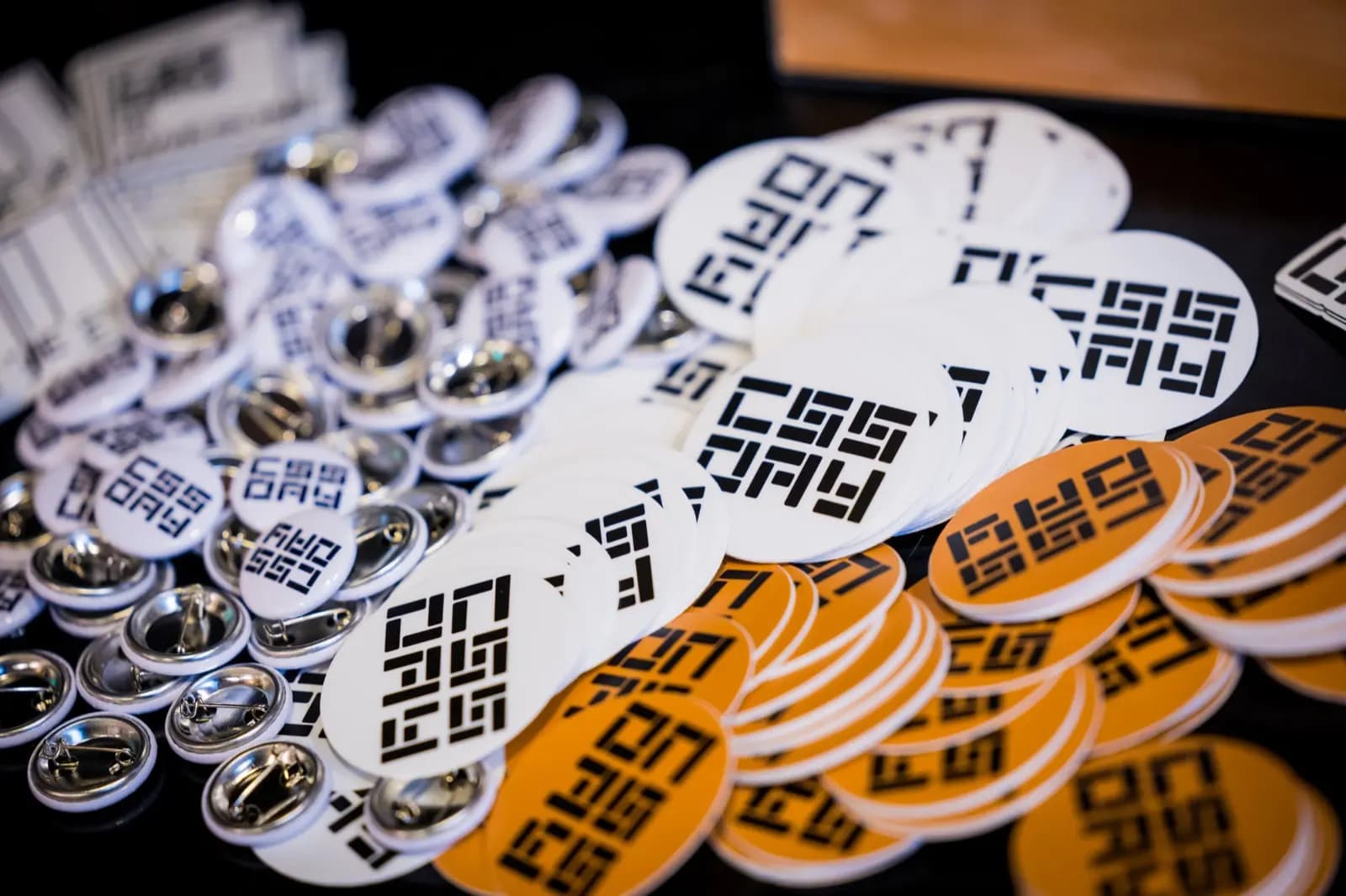 A pile of CSS Day sticker swag is on a table